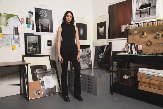 artist standing in studio and images on wall