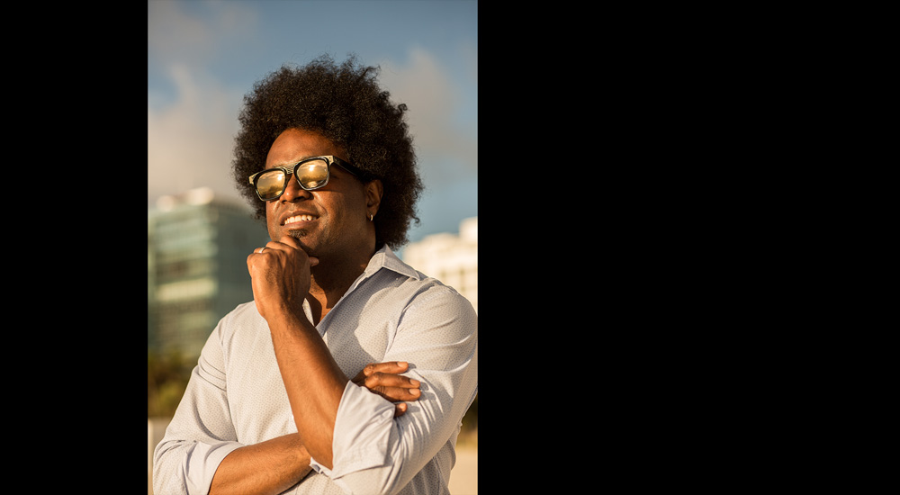 Alexander Arrechea standing in sunshine on a beach with landscape reflected in his sun glasses
